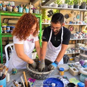 זוג מערבב בטון יחד בידיים בשולחן העבודה בסטודיו