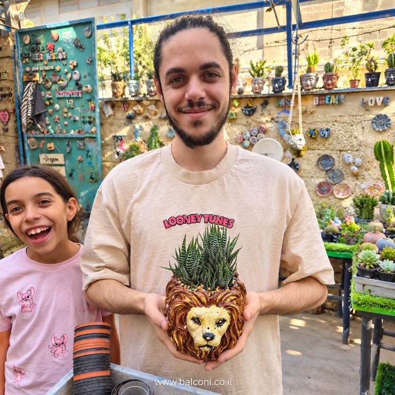 ילדה צוחקת ליד משתתף שמחזיק עציץ בטון בדמות ראש אריה