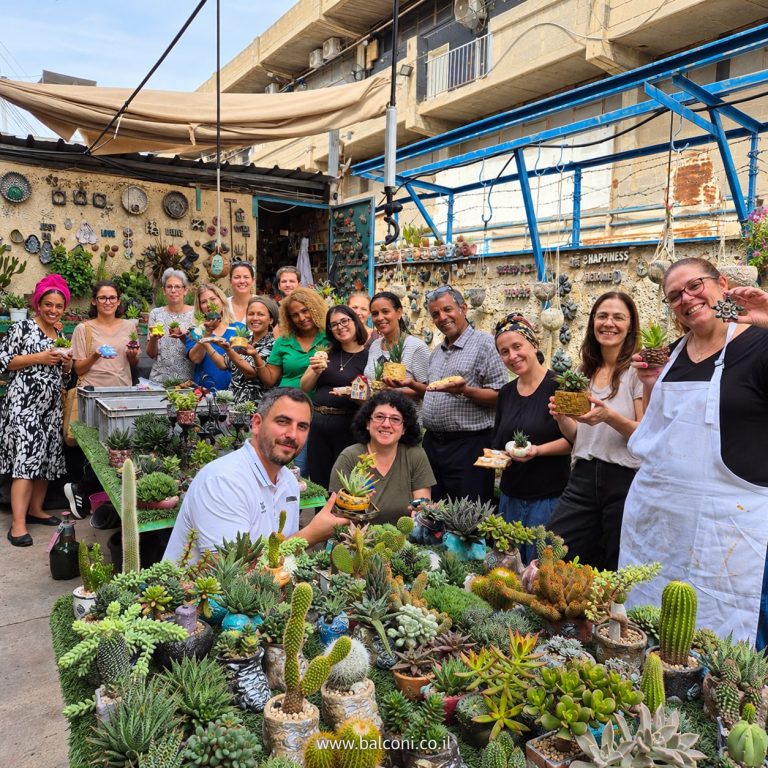 קבוצה גדולה מציגה את עציצי הבטון שיצרה ליד שולחן הסוקולנטים בסטודיו