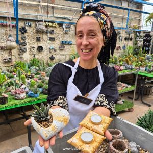 משתתפת מציגה מעמדי נר מבטון בעיצוב כרית בגוון זהב ועציץ לב
