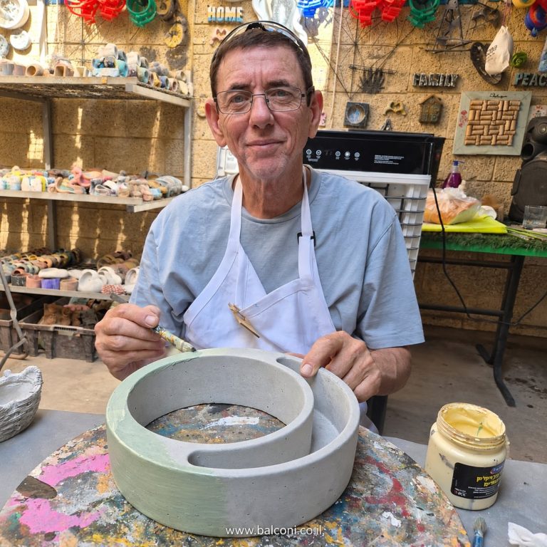 משתתף צובע אדנית בטון עגולה גדולה ליד שולחן העבודה