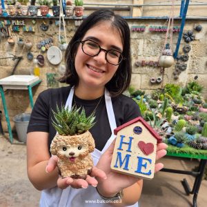 משתתפת מחזיקה עציץ בטון בדמות כלבלב ובית בטון קטן